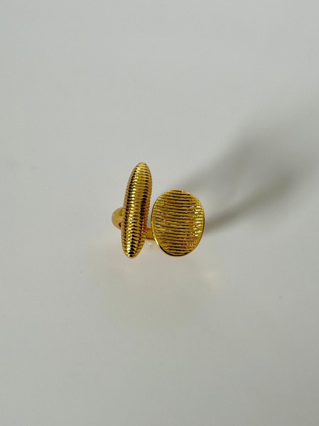 A pair of textured gold stud earrings with a ribbed, hammered finish, displayed on a clean light gray background.