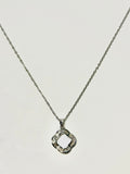 A silver-tone necklace with a delicate chain and a geometric, open quatrefoil pendant embellished with small clear stones, shown against a plain light background.